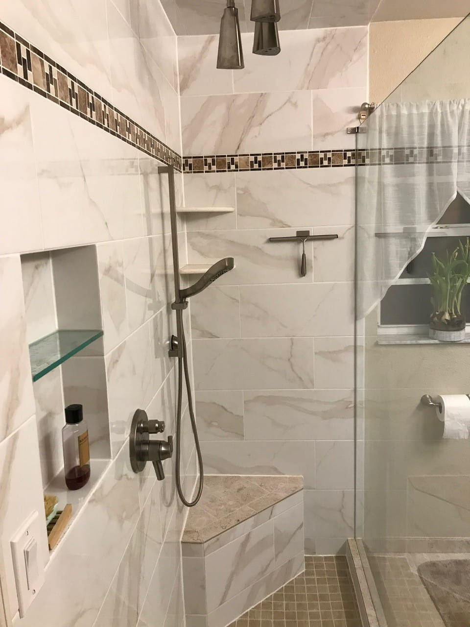 White marble-look shower with mosaic accent band, built-in bench and niche